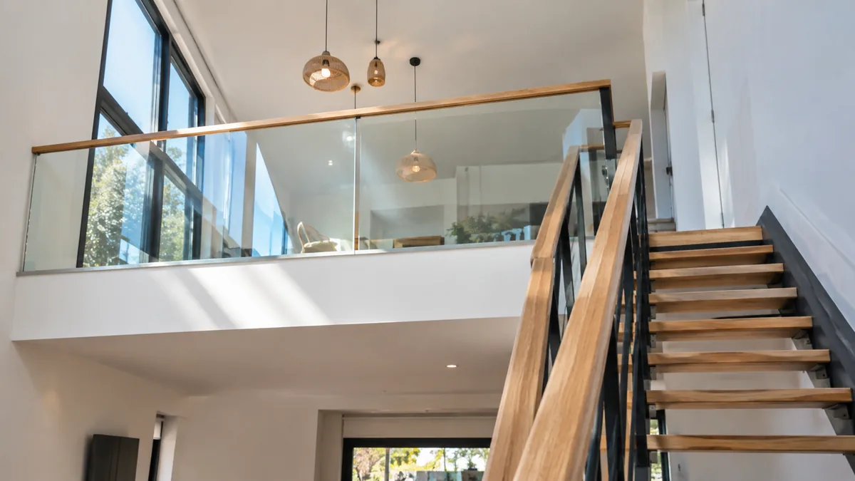 Garde-corps en verre sur muret bas d'une mezzanine et escalier intérieur en bois